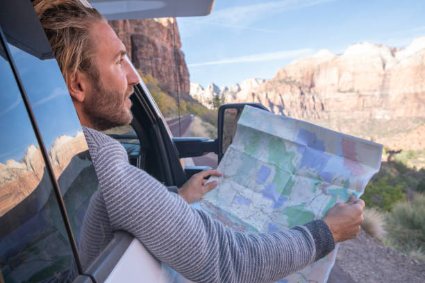 istock Road trip concept; Young man inside camper-van looking at road map for directions exploring national parks and nature ready for adventure. 1147682985