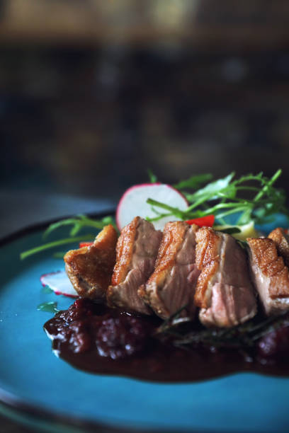 istock Duck confit with salad , baked apple and raspberry sauce served on wooden table 1147683636