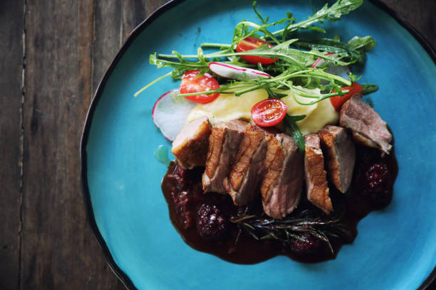 istock Duck confit with salad , baked apple and raspberry sauce served on wooden table 1147683642