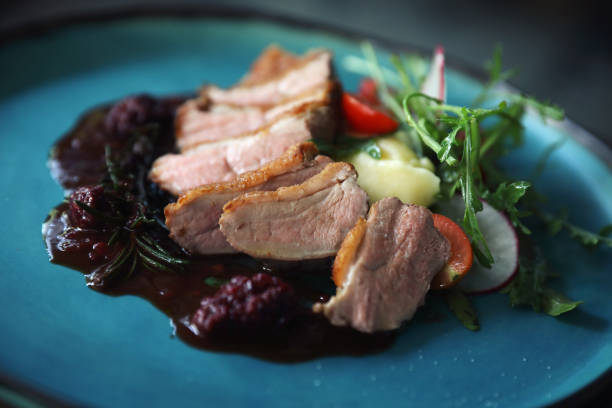 istock Duck confit with salad , baked apple and raspberry sauce served on wooden table 1147683654