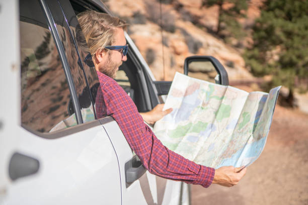 istock Road trip concept; Young man inside camper-van looking at road map for directions exploring national parks and nature ready for adventure. 1147684012