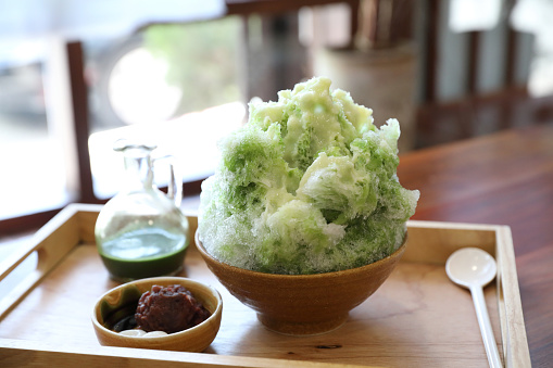 Delicious Japanese sweet shaved ice green tea on wooden table in japanese cafe