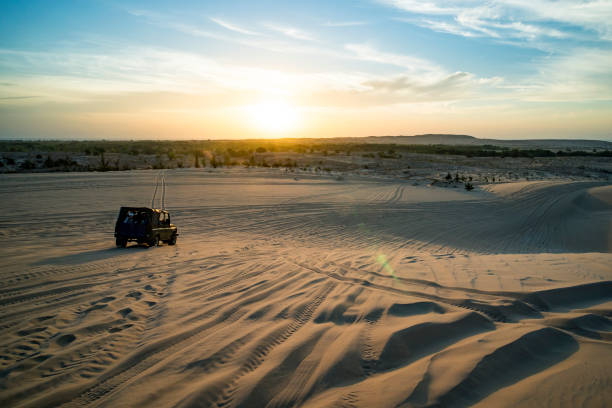 safari nel deserto con auto fuoristrada 4x4 alla luce del sole. tramonto colorato nel deserto. fuoristrada cavalca sulla sabbia tra le dune del deserto nei raggi del sole nascente - 4x4 rally car racing car desert foto e immagini stock