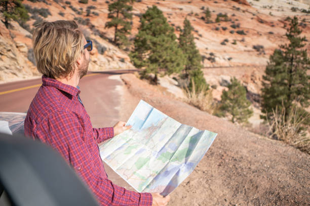 istock Road trip concept; Young man inside campervam looking at road map for directions exploring national parks and nature ready for adventure. 1147693816
