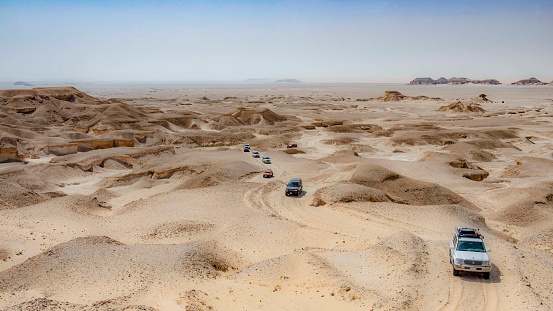 Small SUV 4x4 in Desert Landscape in Middle East. Surreal view of remote location during the day.