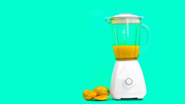 istock mango juice with a blender, isolated on a green background 1147699865