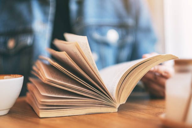 istock a woman holding and reading a vintage novel book 1147701655