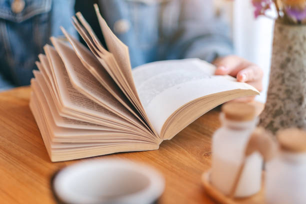 istock a woman holding and reading a vintage novel book 1147701746