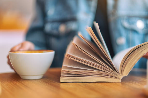 istock a woman holding and reading a vintage novel book 1147701752