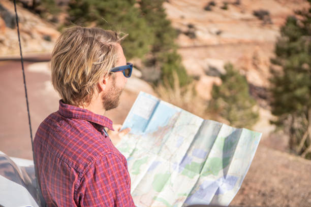 istock Road trip concept; Young man inside campervam looking at road map for directions exploring national parks and nature ready for adventure. 1147701827