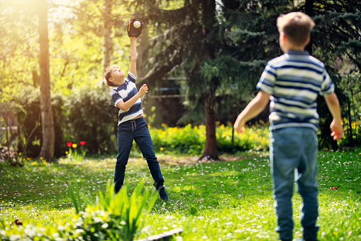 Little boys practicing baseball throws in the back yard.\nNikon D850