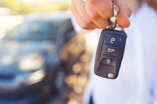 Female car salesperson handing  over the new car keys Female car salesperson handing  over the new car keys. There is a new car behind her out of focus. Close up with Copy space car key photos stock pictures, royalty-free photos & images