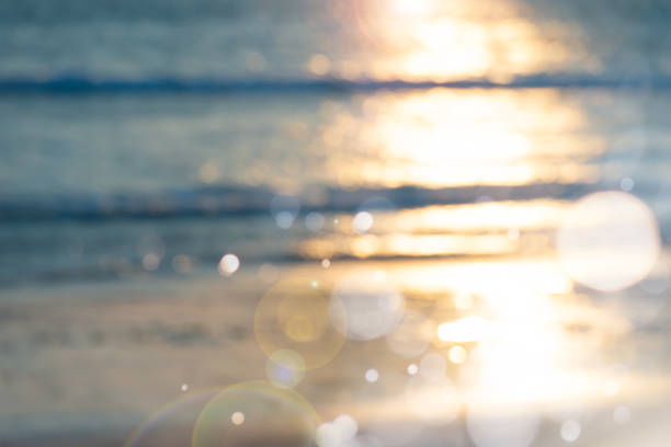 Blur Sea water bokeh and sand beach against sunlight background during sunset. Blur sea water bokeh at sunset