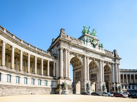 Low angle view of the arcade du Cinquantenaire, the triumphal arch erected in 1905 by king Leopold II in the Cinquantenaire park in Brussels, Belgium, on a sunny day against blue sky.