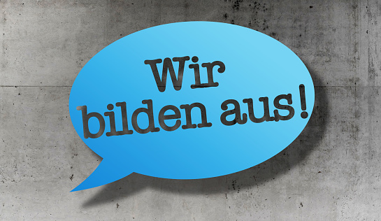 text WIR BILDEN AUS, German for we train apprentices, in speech bubble against concrete wall