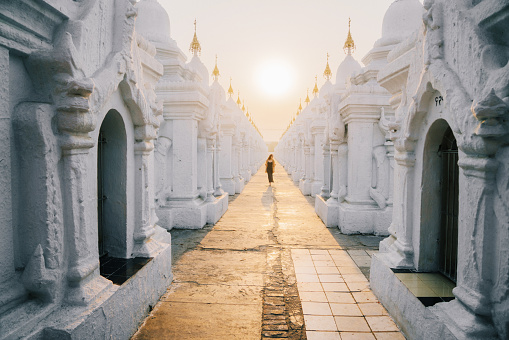 Young Caucasian woman walking in Kuthodaw Pagoda in Mandalay at sunrise, Myanmar