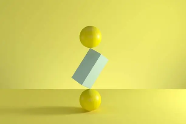 Photo of Stack of two yellow spheres and blue box in the middle isolated on yellow background. Minimal concept idea. 3D Render.