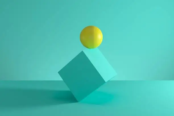 Photo of Yellow sphere on the edge of blue cube isolated on green background. Minimal concept idea. 3D Render.