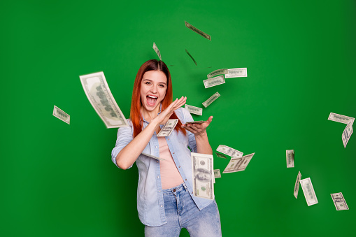 Portrait delighted ecstatic lady hold hand get salary wages rich aim positive cheerful satisfied content beautiful trendy stylish wear jeans long straight hairstyle isolated on green background.