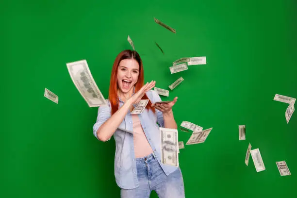 Photo of Portrait delighted ecstatic lady hold hand get salary wages rich aim positive cheerful satisfied content beautiful trendy stylish wear jeans long straight hairstyle isolated on green background