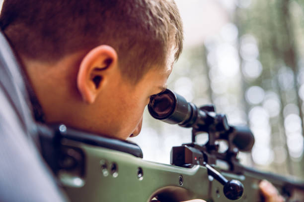 teenager boy aiming a sports rifle to shoot at a target