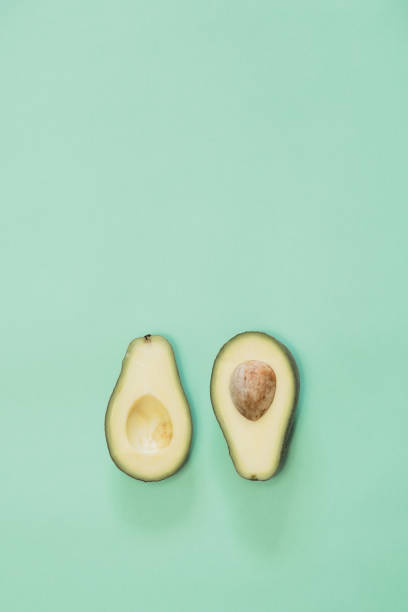 istock Avocado cut in half on green background  with copy space 1147734598