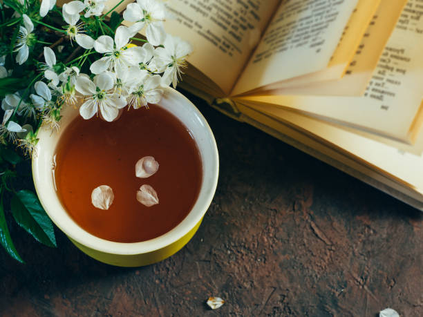 istock Spring Cup of tea and an old book on the table with cherry blossoms 1147738203