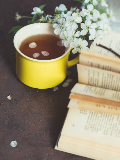 istock Spring Cup of tea and an old book on the table with cherry blossoms 1147738226