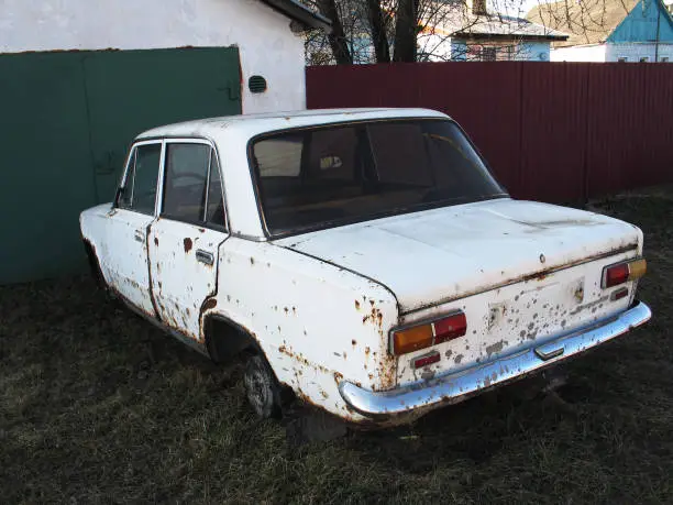 pictured in the photo old rusty white car without wheels outdoor