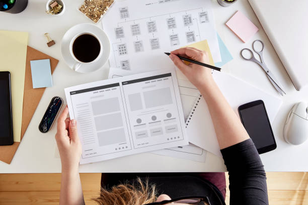 Wireframing stage of a web design project Overhead view of young UX designer planning out the structure of a website. Wireframing stage of a web design project website wireframe photos stock pictures, royalty-free photos & images
