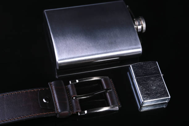 istock Stainless hip flask, lighter and luxury belt isolated on mirror black background. 1147740153