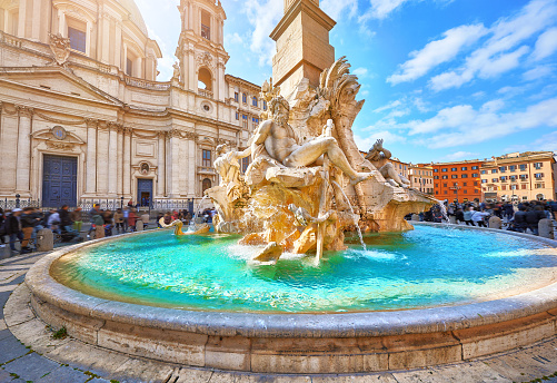 Rome, Italy. Fountain of the Four Rivers on Piazza Navona. Ancient fountain, statues, obelisk design of Bernini. Famous landmark touristic location near Sant Agnese in Agone church. Sunny summery day.