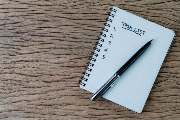 istock Task List, project management concept, pen on white paper notepad with handwritten headline as Task List and numbers listed on wood table, writing business project with tasks prioritize 1147744145