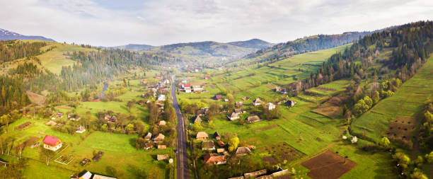 Road in mountain village. Aerial Panorama of Carpathian valley. Road in mountain village. Rural spring misty landscape. Aerial Panorama of Carpathian valley. ukrainian village stock pictures, royalty-free photos & images