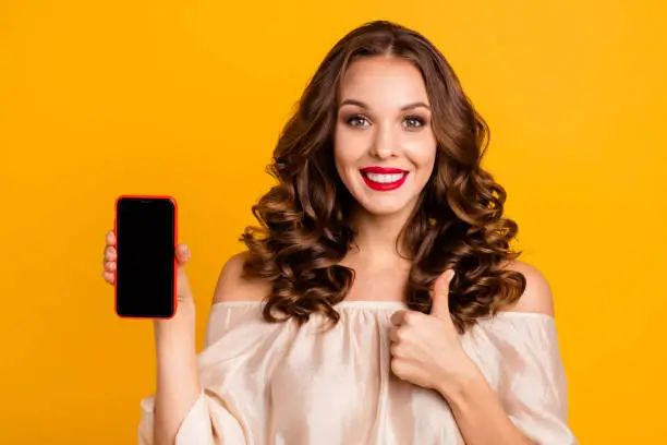 Close-up portrait of nice attractive lovely cheerful cheery wavy-haired lady using new cool 5g app internet online showing thumbup advice ad isolated over bright vivid shine yellow background.
