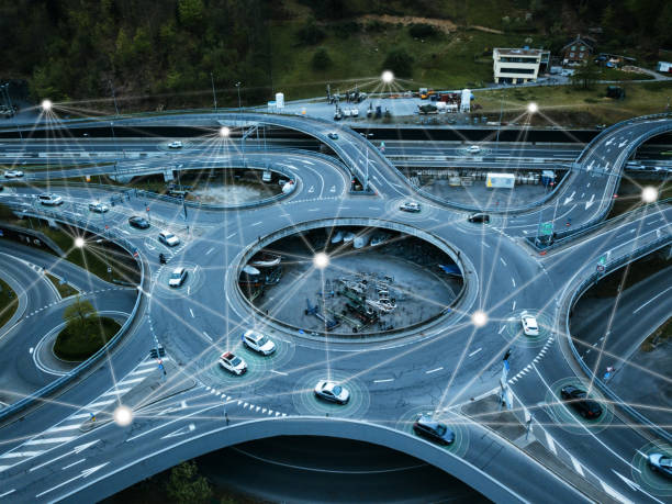 Autonomous self driving cars in a roundabout (traffic circle) next to a highway. The cars are connected with each other with lines illustrating data transfers, GPS information and artificial intelligence used in the future of self driving cars.