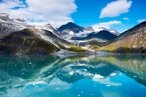 Beautiful view of it Kroderenmeer in Norway. The bushes and boats in the foreground and the high mountains in the background.  A few clouds are visible in the blue sky.