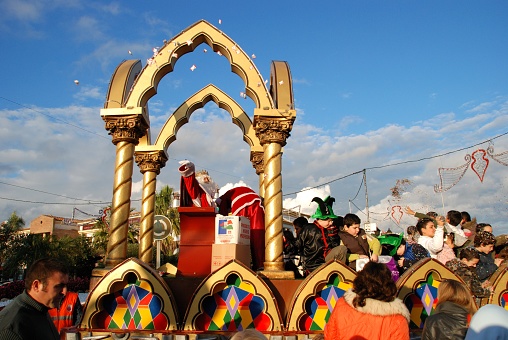 Three Kings Parade with Melchor sitting in his carriage throwing sweets to the public, La Cala de Mijas, Costa del Sol, Malaga Province, Andalucia, Spain, Europe.