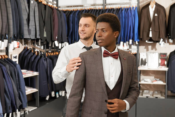 istock Young man trying on and choosing suit in shop. 1147758525