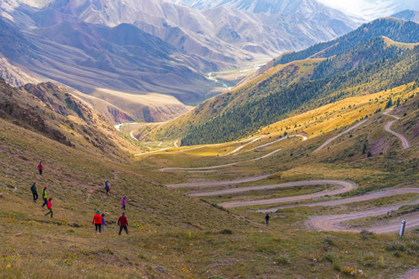 Big group of tourists walking down the 33 parrots pass, a mountain winding road in between Naryn and lake Song-kol in kyrgyzstan.