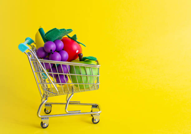istock Mini shopping trolley on yellow background with fruits 1147762761