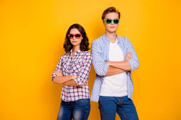 Close up photo of pair in summer specs he him his she her lady boy hands crossed standing back to back self-confident examiners wearing casual plaid shirts outfit isolated on yellow background. cerca de la foto de la pareja en las especificaciones de verano que él su ella ella sus manos de niño cruzado de pie de espaldas a los examinadores con confianza en sí mismos que usan camisas de cuadros ocasionales vestido aislado en el fondo amarillo
