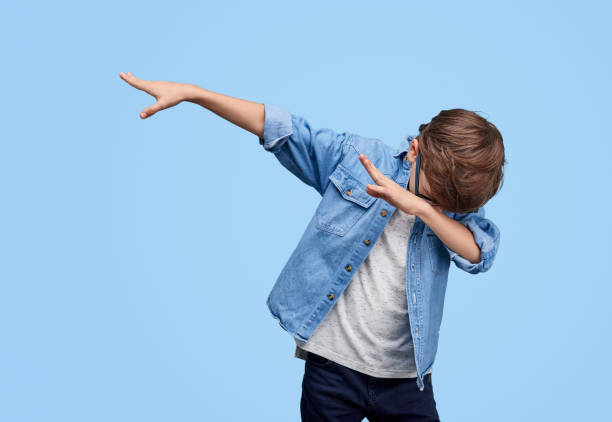 Stylish kid performing dab dancing Little cool boy in glasses and denim jacket dabbing while posing on blue background dab dance stock pictures, royalty-free photos & images