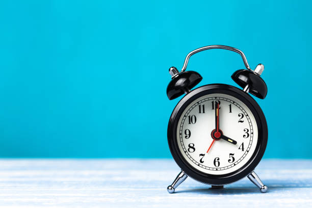 istock Retro black alarm clock on blue background with copy space. Alarm at 7 o'clock clock hand at 4 o'clock 1147768897