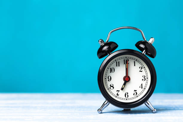 istock Retro black alarm clock on blue background with copy space. Alarm at 7 o'clock clock hand at 7 o'clock 1147768923
