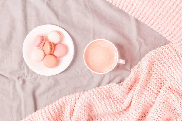 istock Bed with pink knitted plaid, coffee and macaroons 1147769449