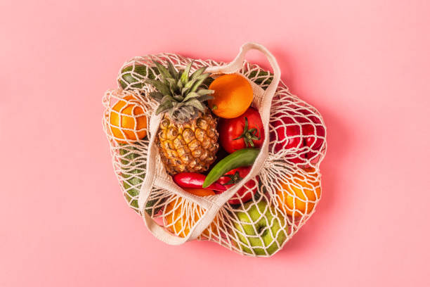 свежие овощи и фрукты в мешочных сетках - basket of fruits стоковые фото и изображения