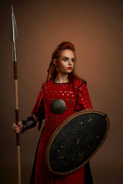 istock Female warrior keeping spear and shield and posing 1147771042