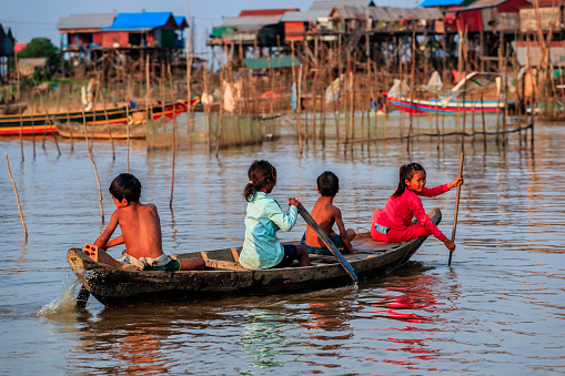 Group of happy Cambodian children rowing a boat on Tonle Sap, Cambodia