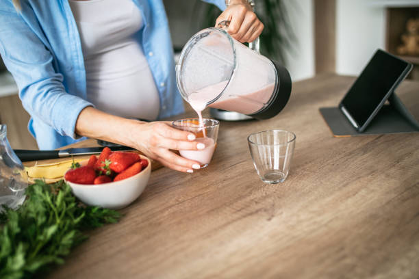 istock Beautiful pregnant woman making smoothie 1147774174